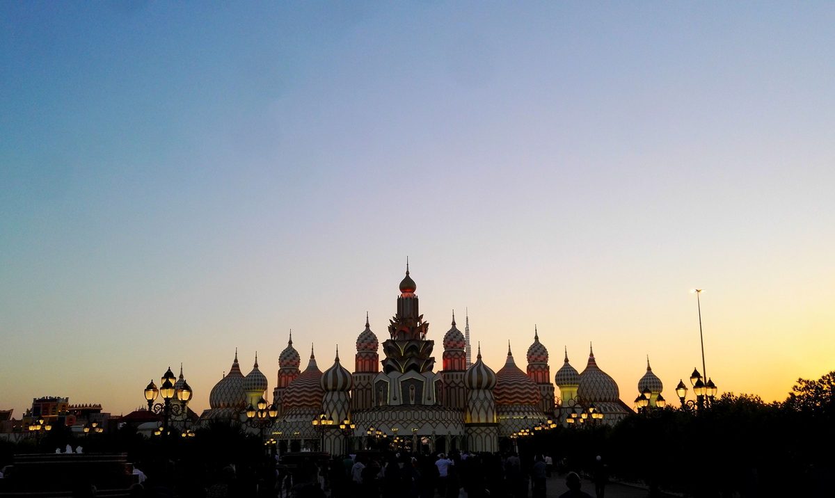 The domed entrance pavilion of Global Village in silhouette against a dusk sky