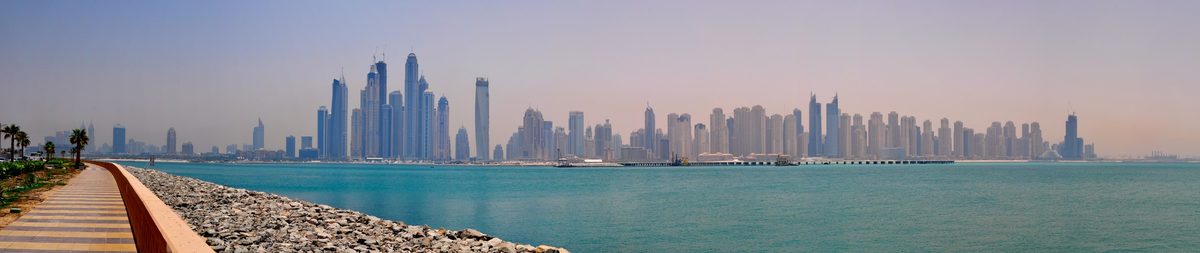 The Dubai Marina and JBR skyline across the water from a seafront walkway